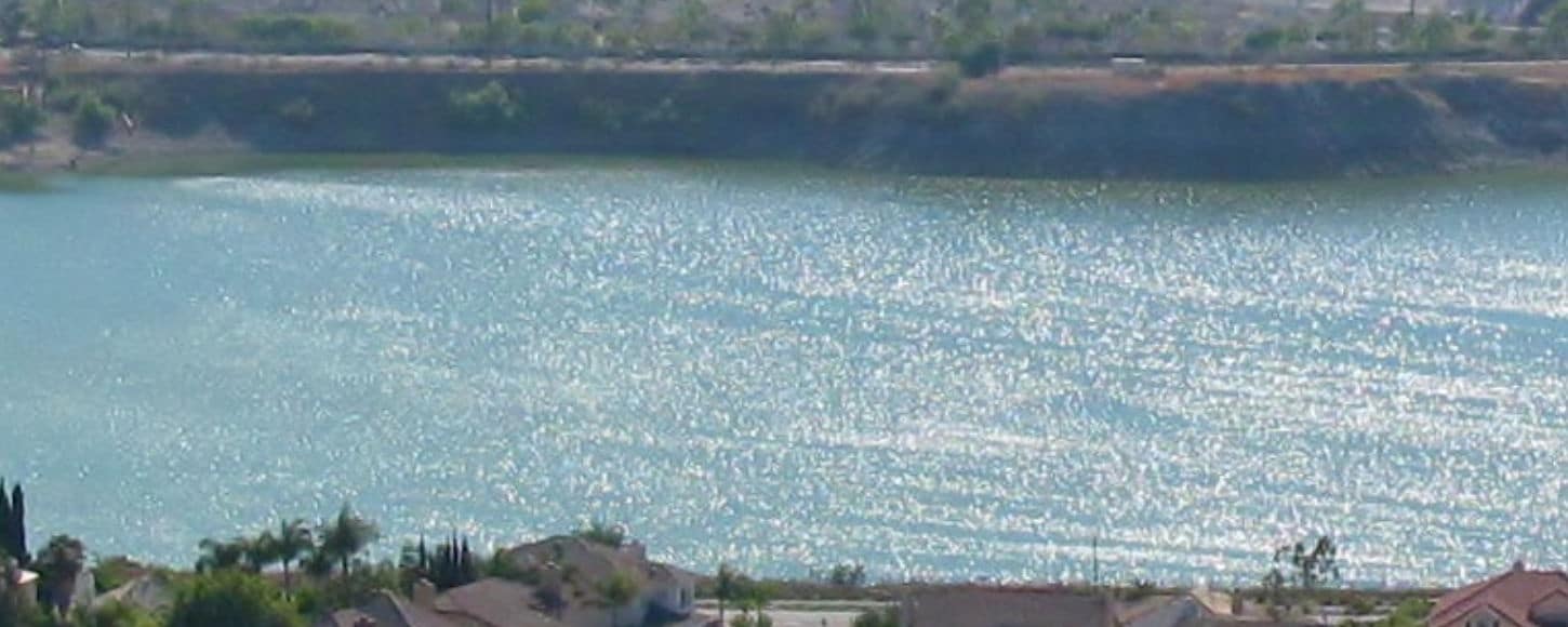 A picture of a body of water, likely a lake, in front of a residential area