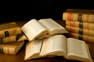 Law Books on a table, some stacked on top of each other and 4 opened